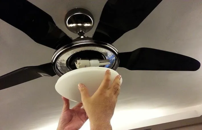 Ceiling fan electrician installing a modern ceiling fan in a living room for improved air circulation.