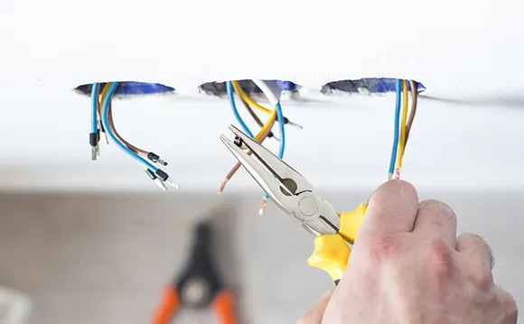 A lighting repair expert is fixing the electric wires of the light fixture.