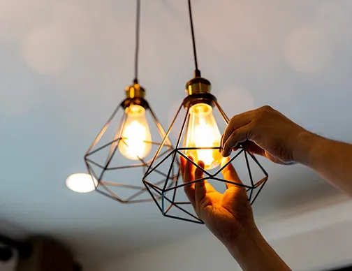 Skilled lighting fixtures electrician professionally installing a new light fixture in a living room.